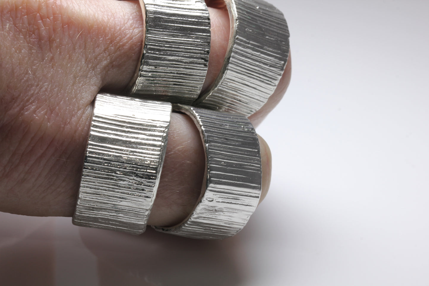 Picture of very large silver rings being worn on. Would suit biker or rock and roll person.