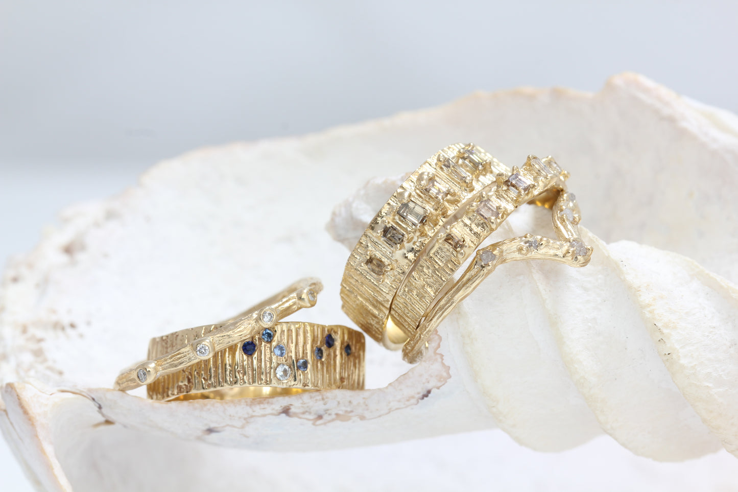 Stack of unique gold wedding bands with diamonds and sapphires.