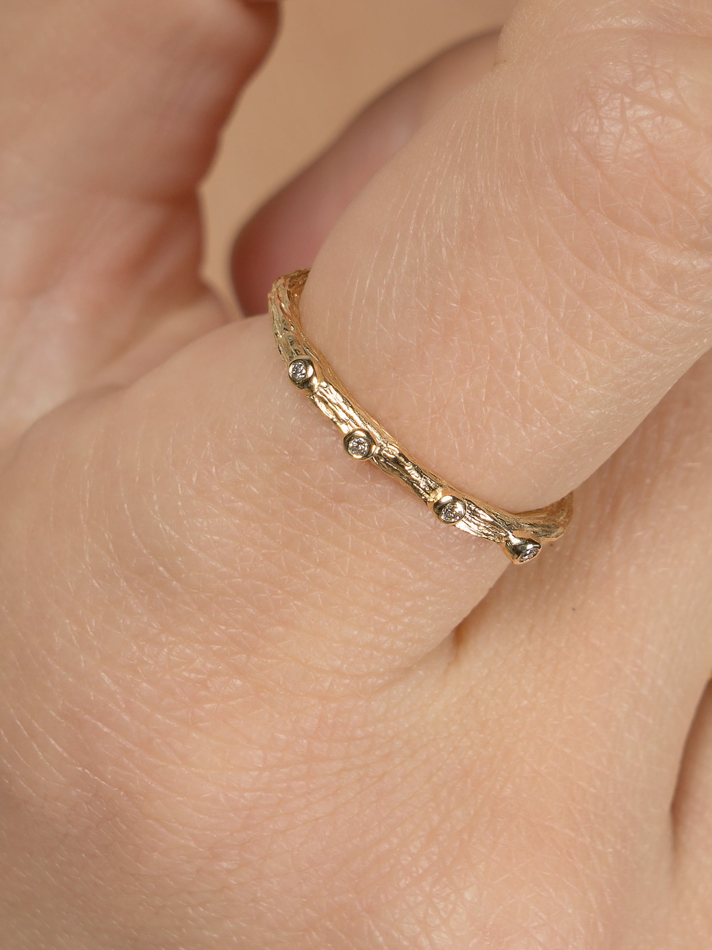 Close of shot of alternative wedding ring textured like a twig in gold with diamonds