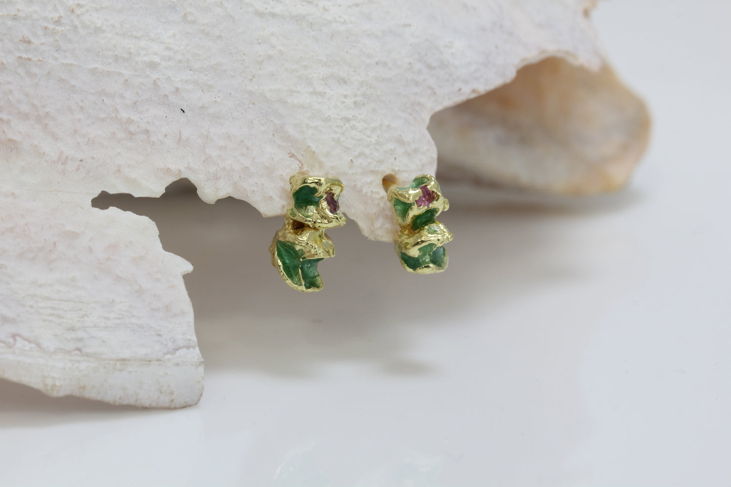 One pair of contemporary jewellery earrings handmade by eily o connell in Bristol with green enamel and pink sapphires.