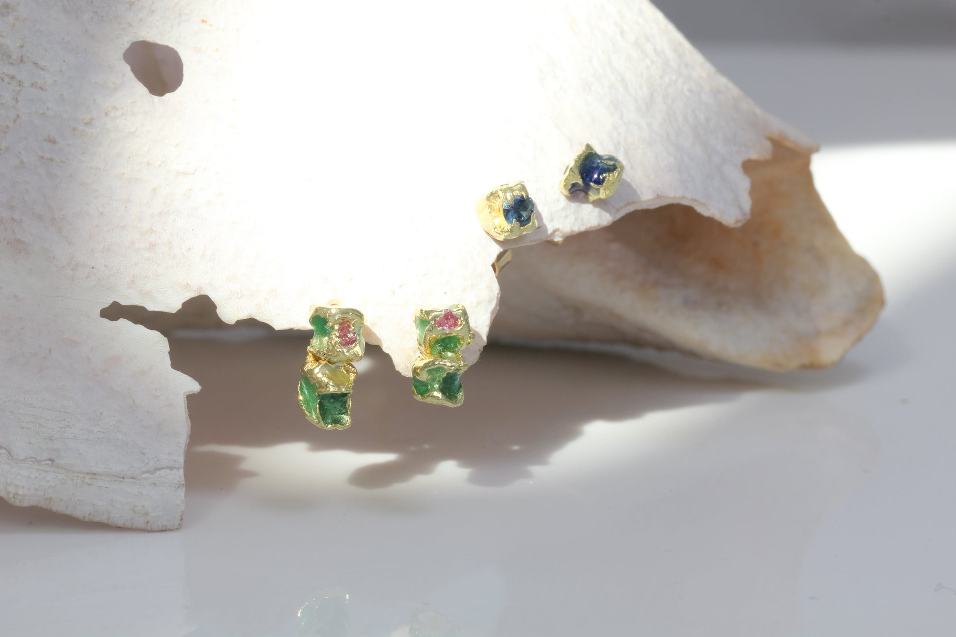 18 carat yellow mis matched earring studs with blue enamel and blue sapphire. Also showing floral pair with green and pink enamel and pink sapphire.