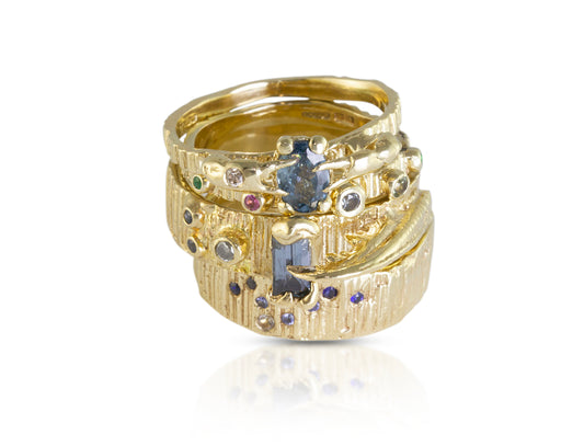 Stack of gold rings with multi coloured sapphires in blue and pink and green. Sea inspired ring stack with lots of texture. Handmade by irish jeweller, based in Bristol Eily O Connell.