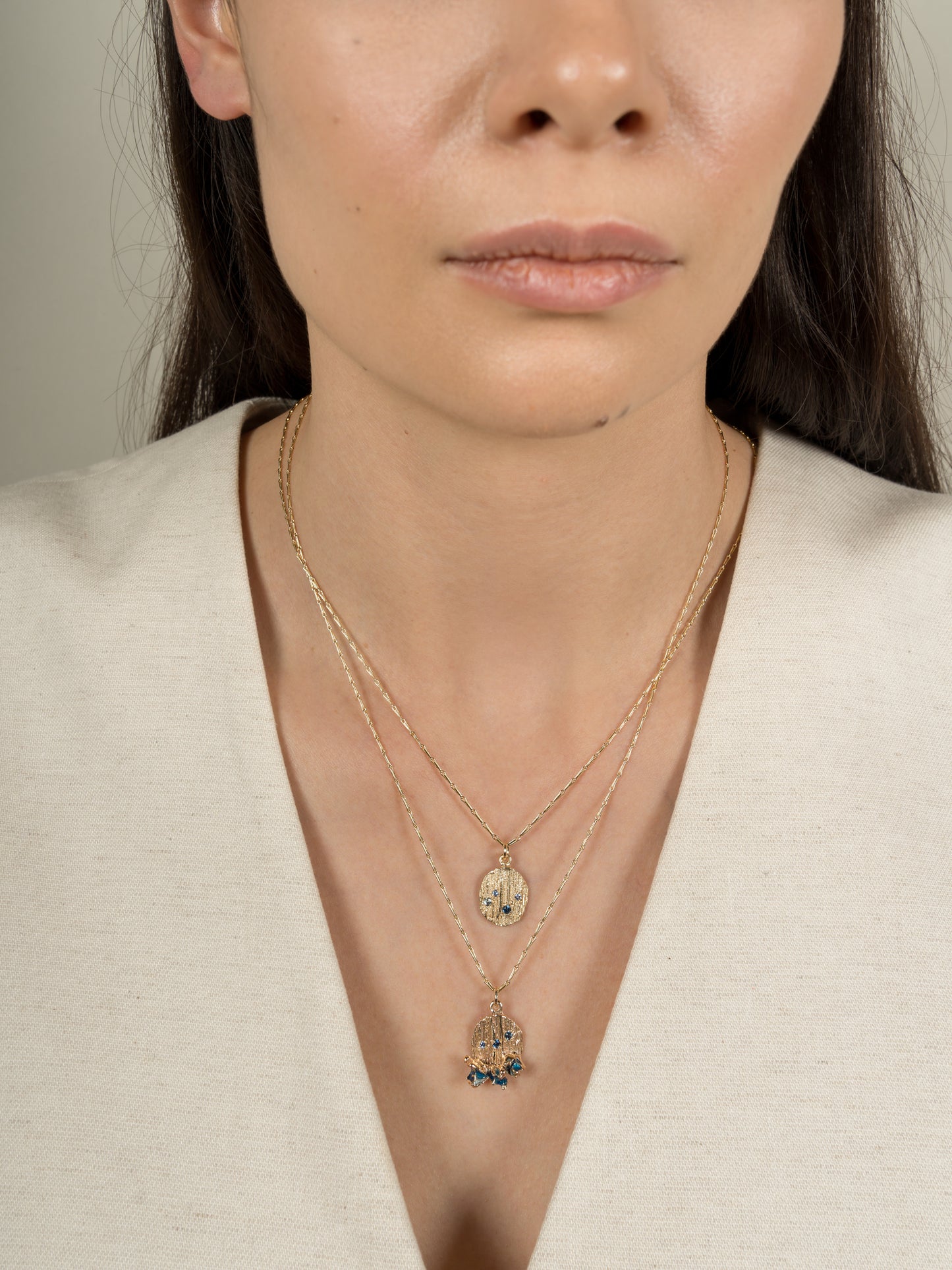 Model wearing handmade layered gold necklaces with sapphires and enamel.