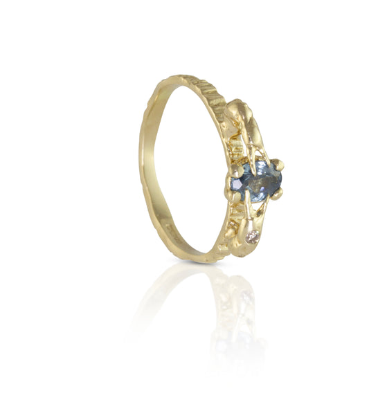 Alternative engagement ring with blue sapphire and champagne diamond with crab claws holding the blue precious gemstone.