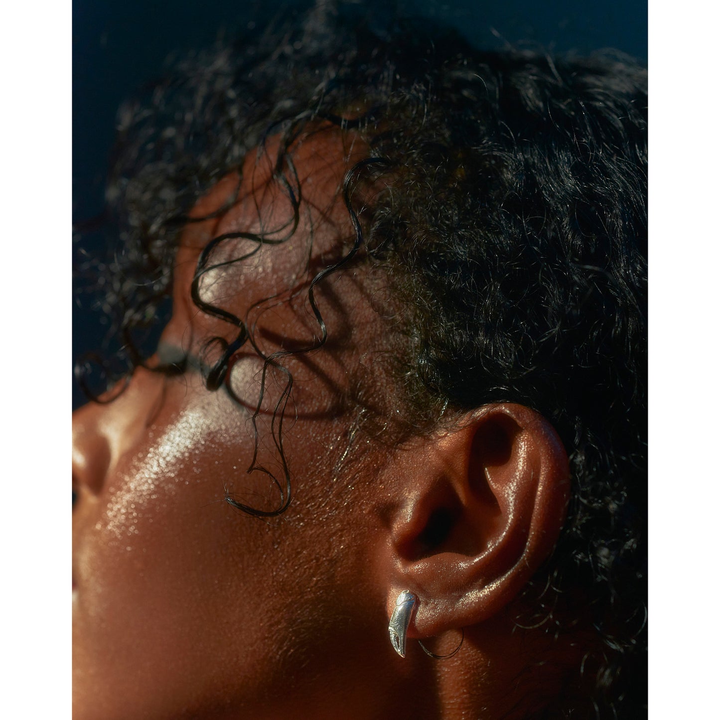 A pair of silver stud earrings cast from tiny crab claws into solid silver shown on a models ear