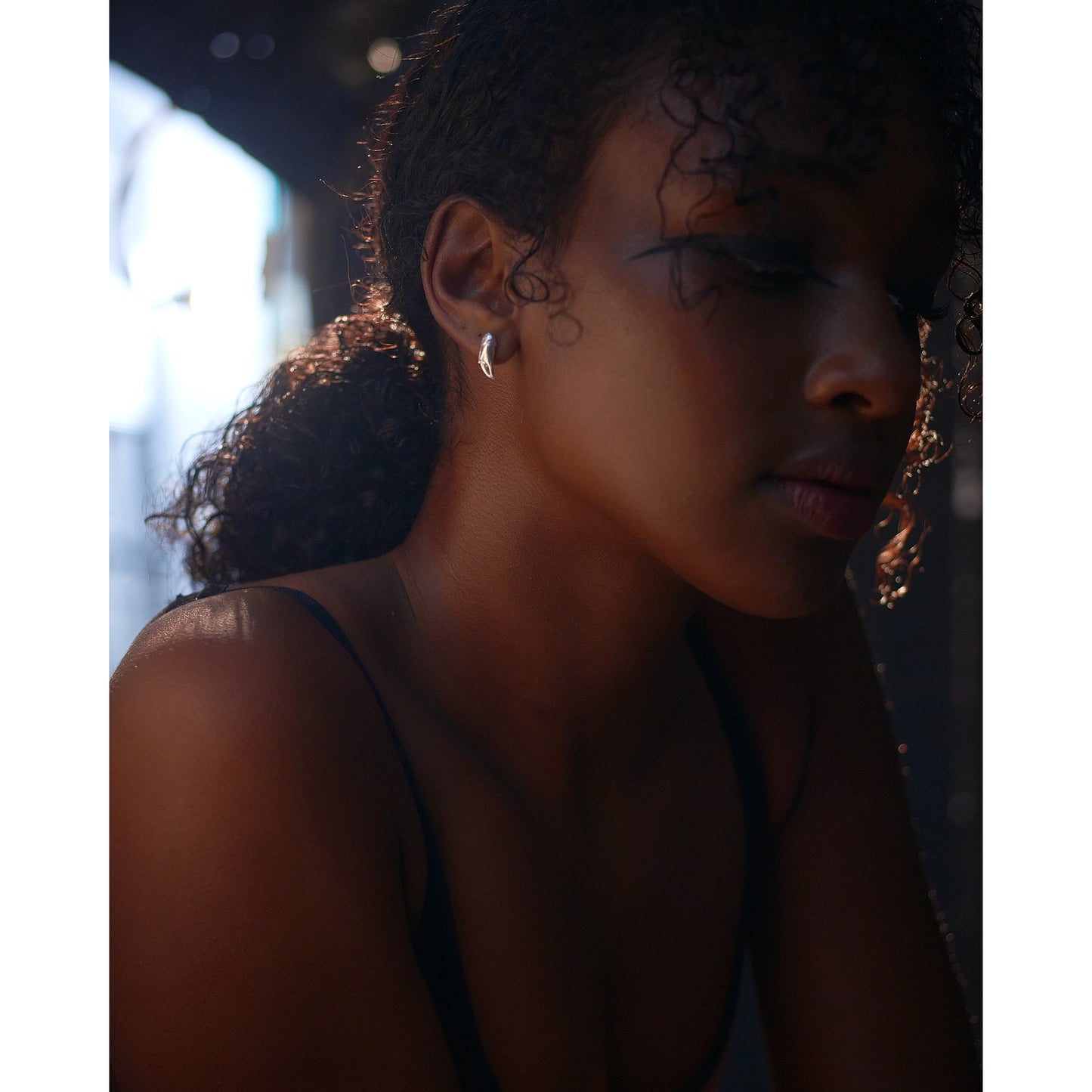 A pair of silver stud earrings cast from tiny crab claws into solid silver shown on a models ear