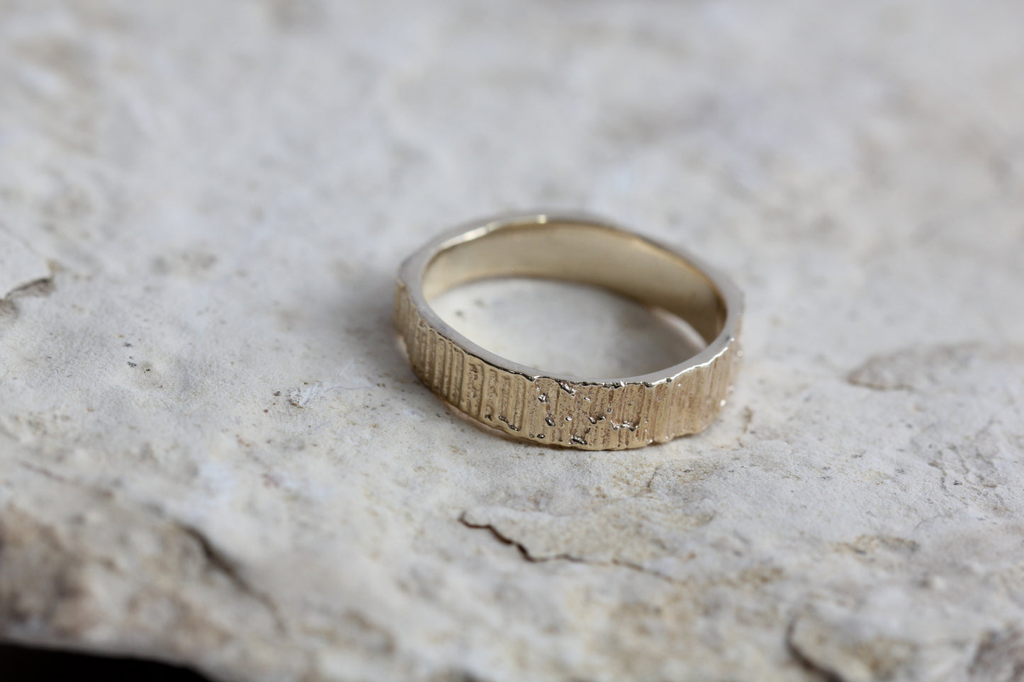 Alternative wedding band or gold ring with organic textures sitting on a rock. Handmade by Irish jeweller Eily O Connell.ll
