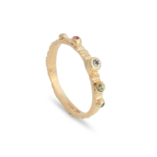 Alternative wedding band in gold set with various coloured sapphires and emerald gemstones in a rainbow of colour.
