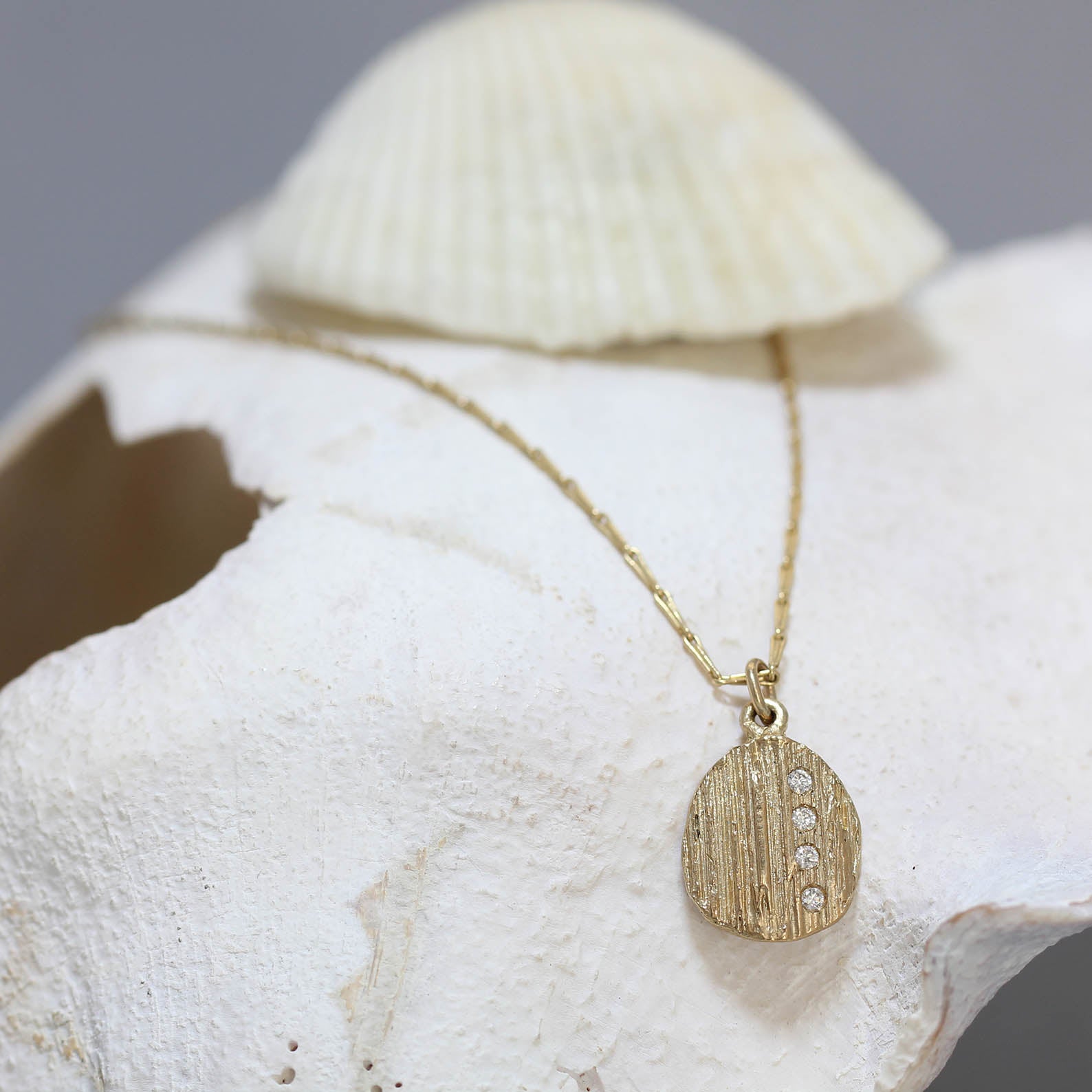 Gold necklace set with diamonds pictured here on a shell. 