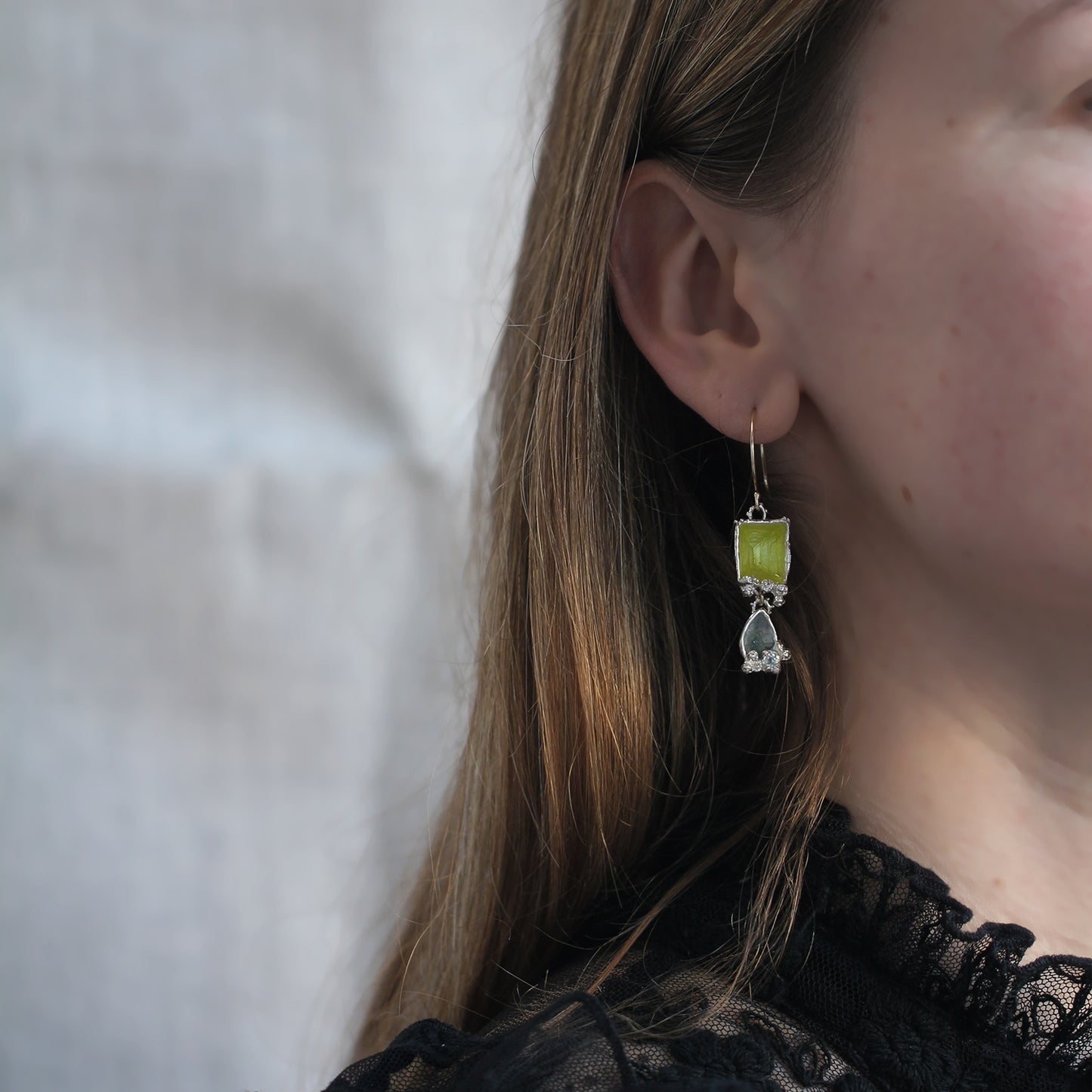 Handmade drop earrings in fine silvera nd gold on a model with neon yellow enamel and aquamarine. 