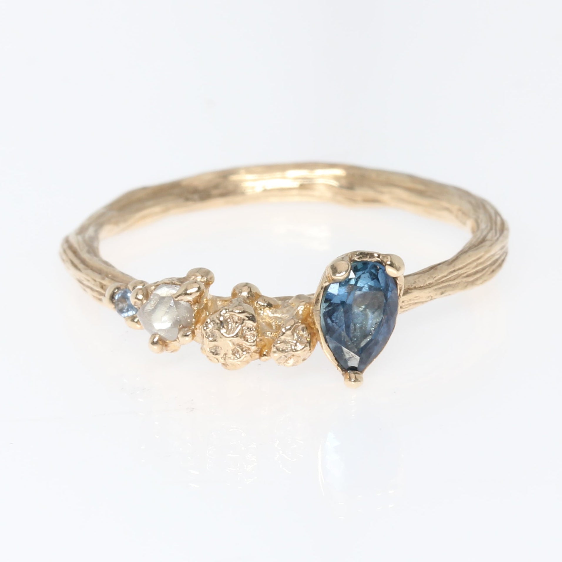 Gold ring with a blue gemstone on a white background