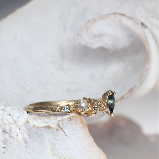 Gold ring with a blue sapphire gemstone on a white shell