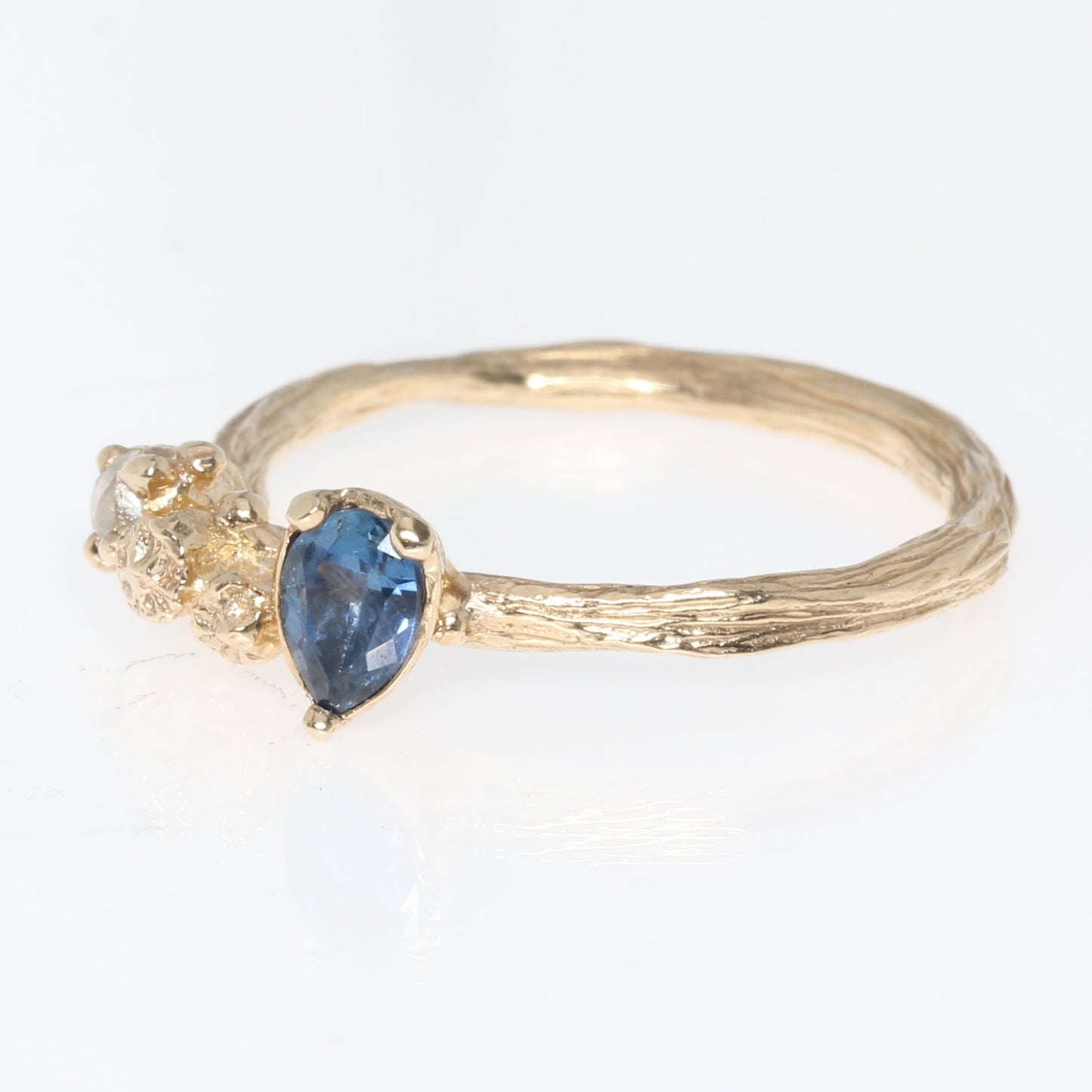 Gold engagement ring with a blue sapphire gemstone on a white background