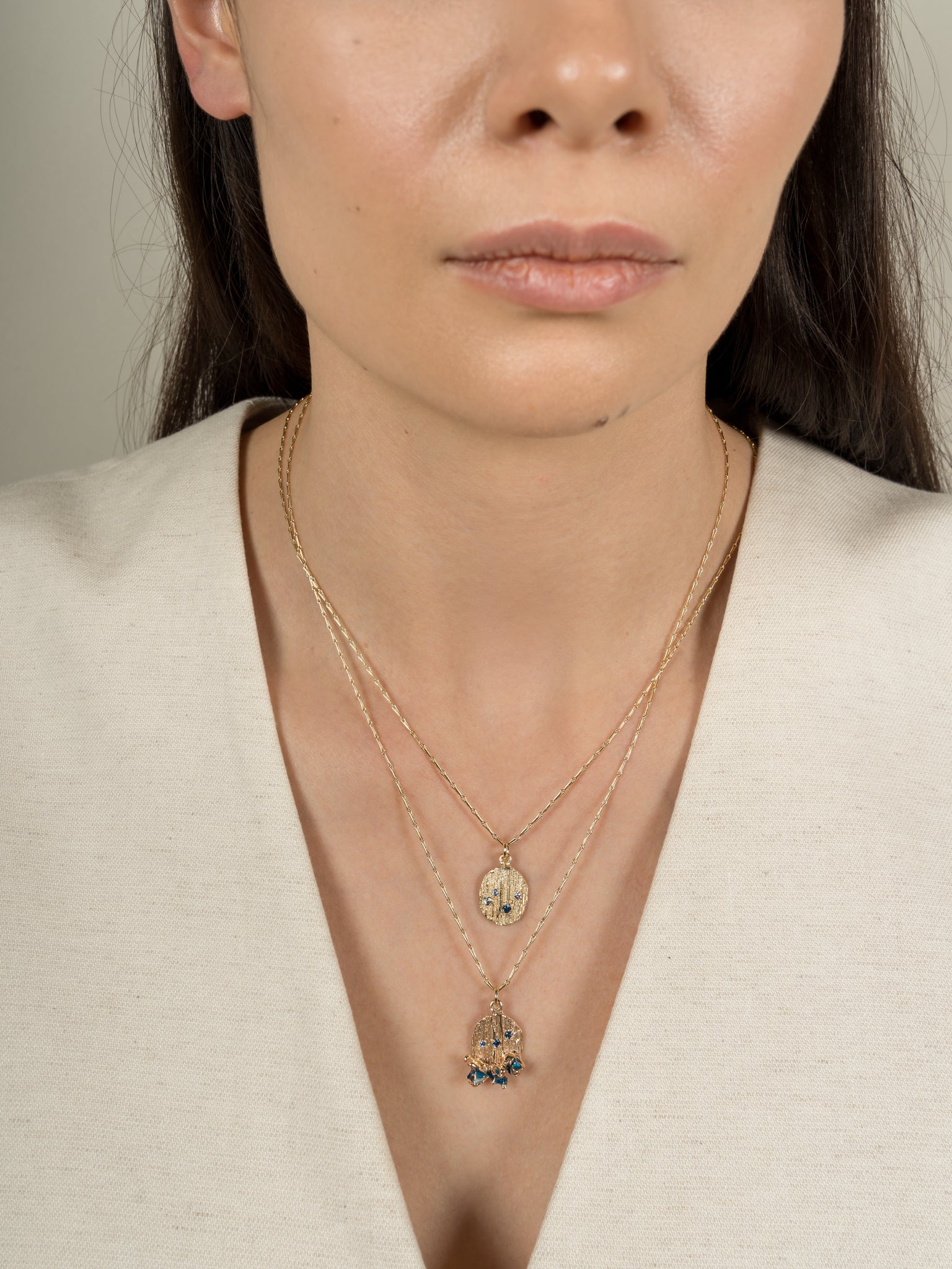 Model wearing handmade layered gold necklaces with sapphires and enamel. 