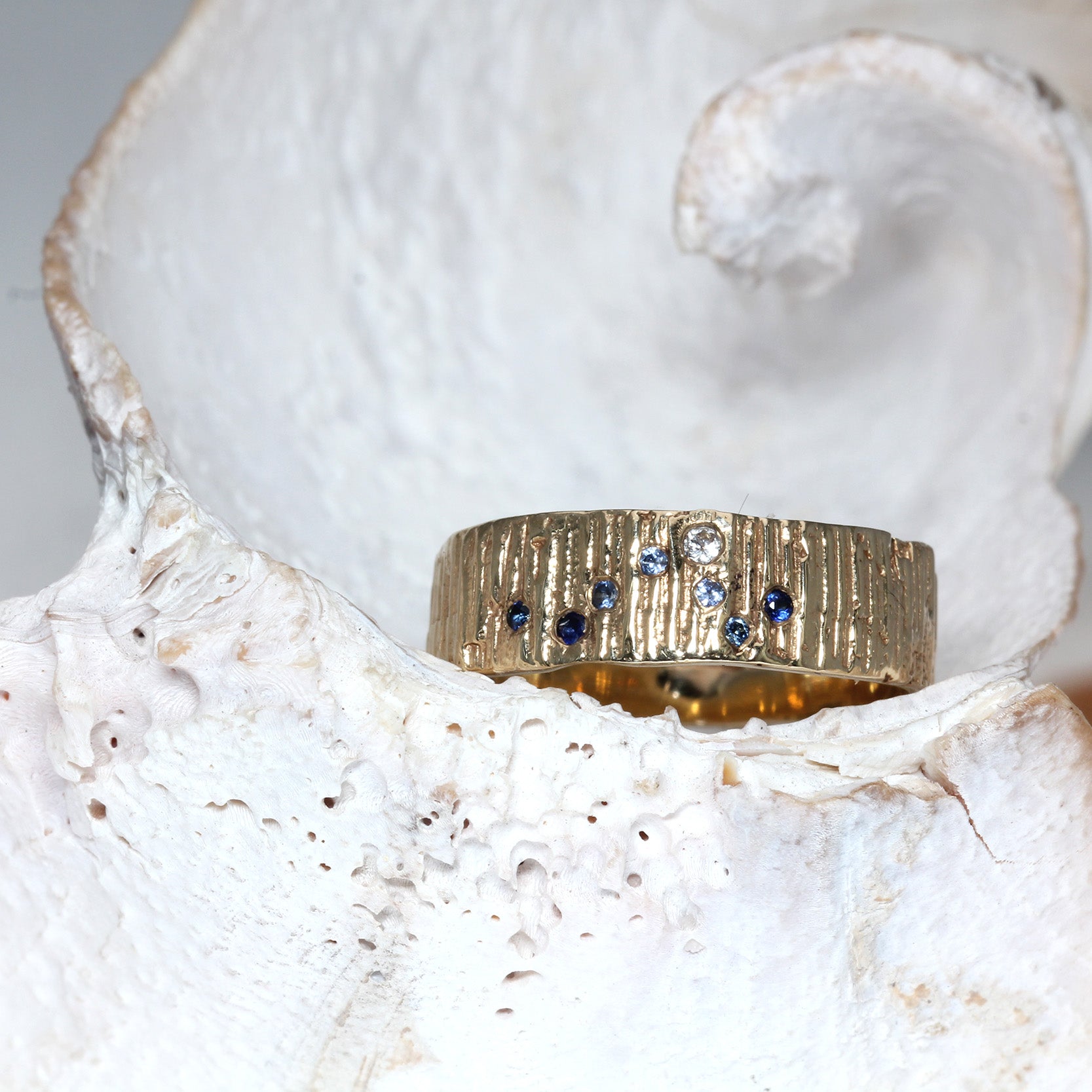 Gold thick wedding ring with sapphires in the shape of a wave on a seashell.  Perfect surfer girl ring.