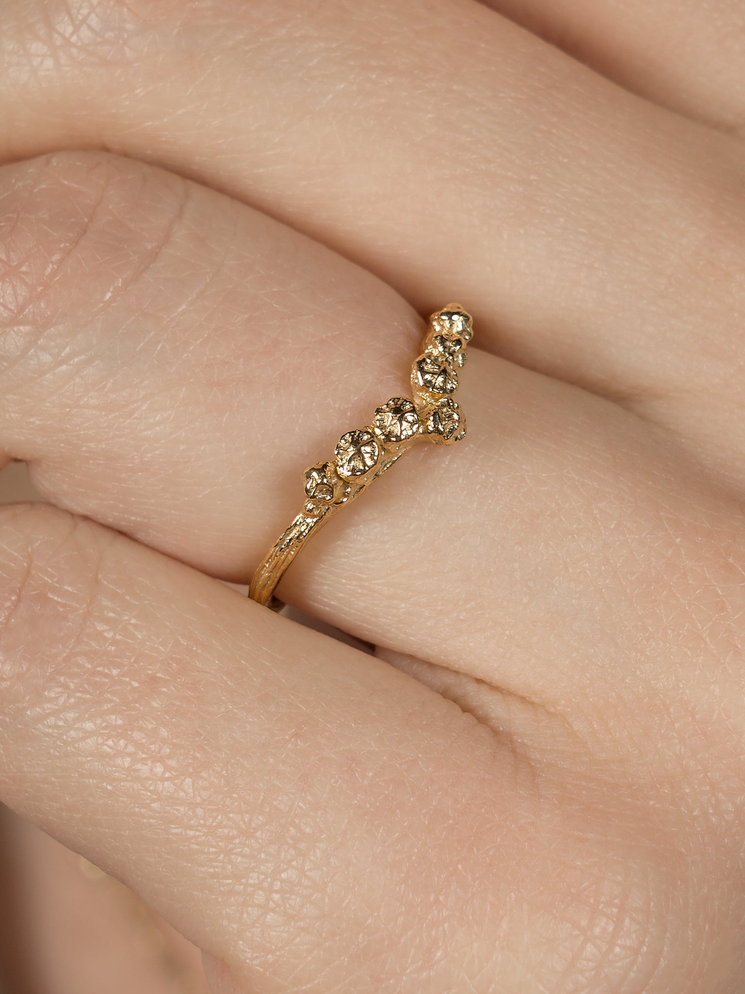 Chevron V shape gold ring cast from twigs and berries close up being worn on hand