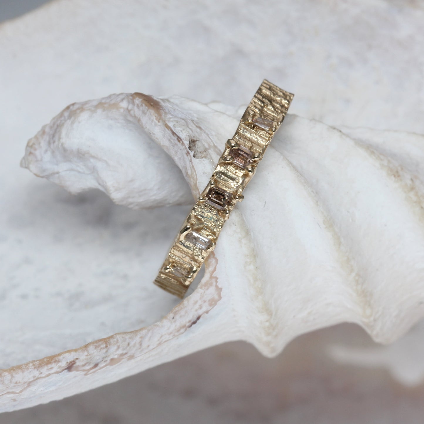 Gold ring with embedded champagne diamonds stones on a white shell
