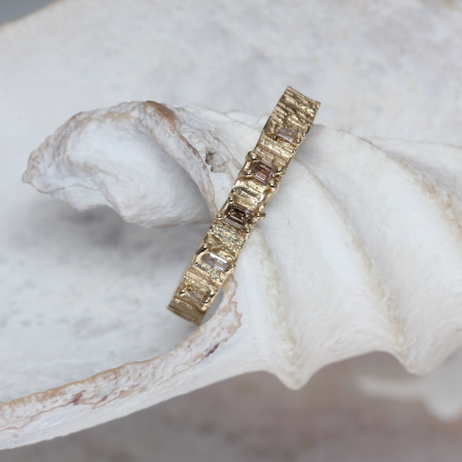 Gold ring with embedded champagne diamonds stones on a white shell