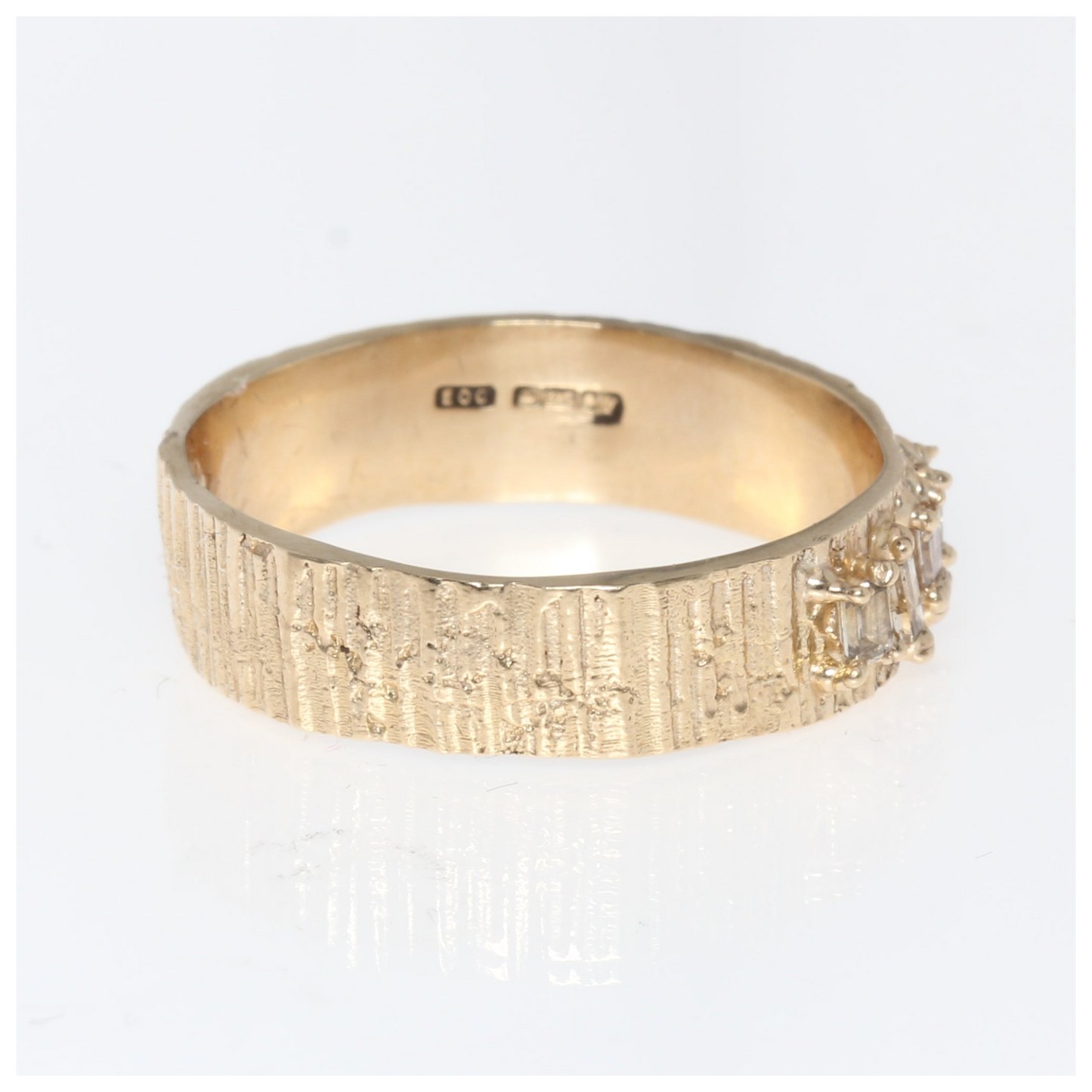 Gold ring with textured band on a white background