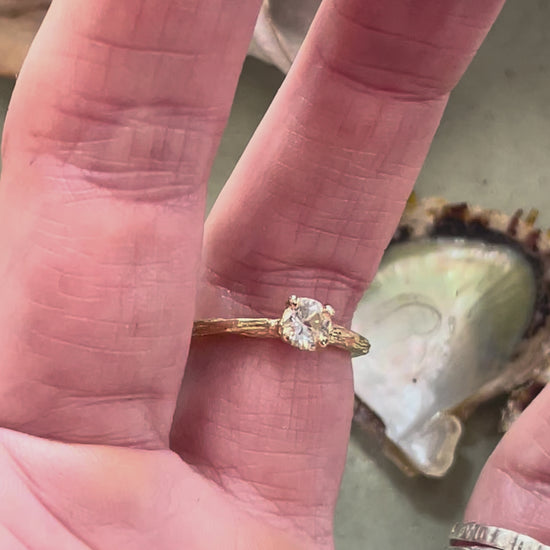 gold organic textured ring with cast berry on top of a white sapphire. Nice alternative to a diamond solitaire ring. Perfect alternative engagement ring. Being worn here. 