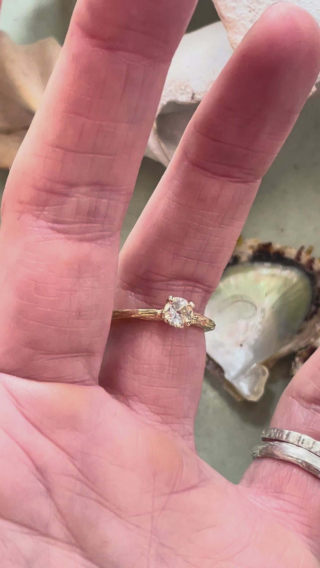 gold organic textured ring with cast berry on top of a white sapphire. Nice alternative to a diamond solitaire ring. Perfect alternative engagement ring. Being worn here. 
