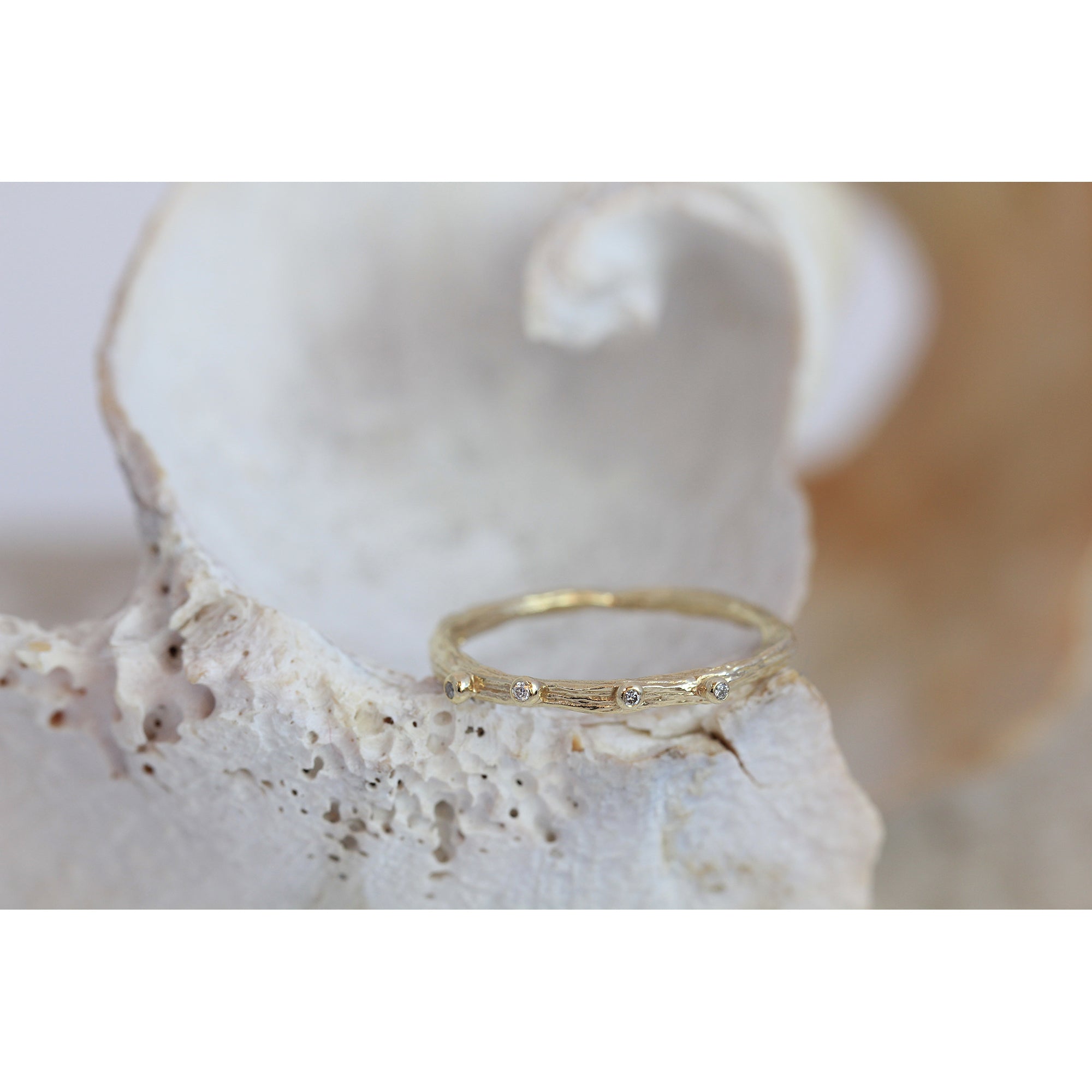 Dainty gold ring cast from a twig with tiny diamonds on the top. Handmade in Bristol by Irish jeweller Eily o connell. In this picture it is sitting on a shell.