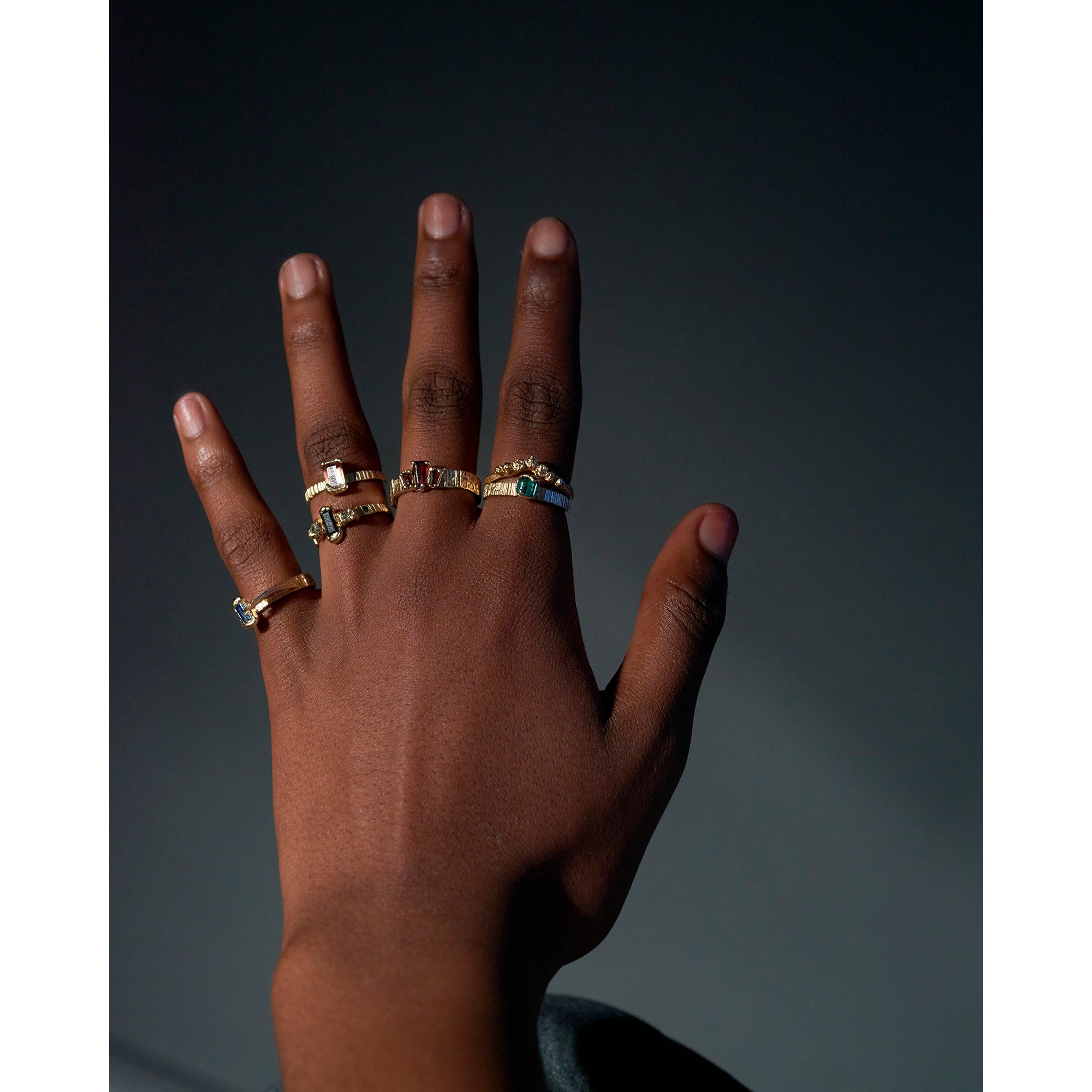 Lots of organic gold rings being worn on a models hand. 