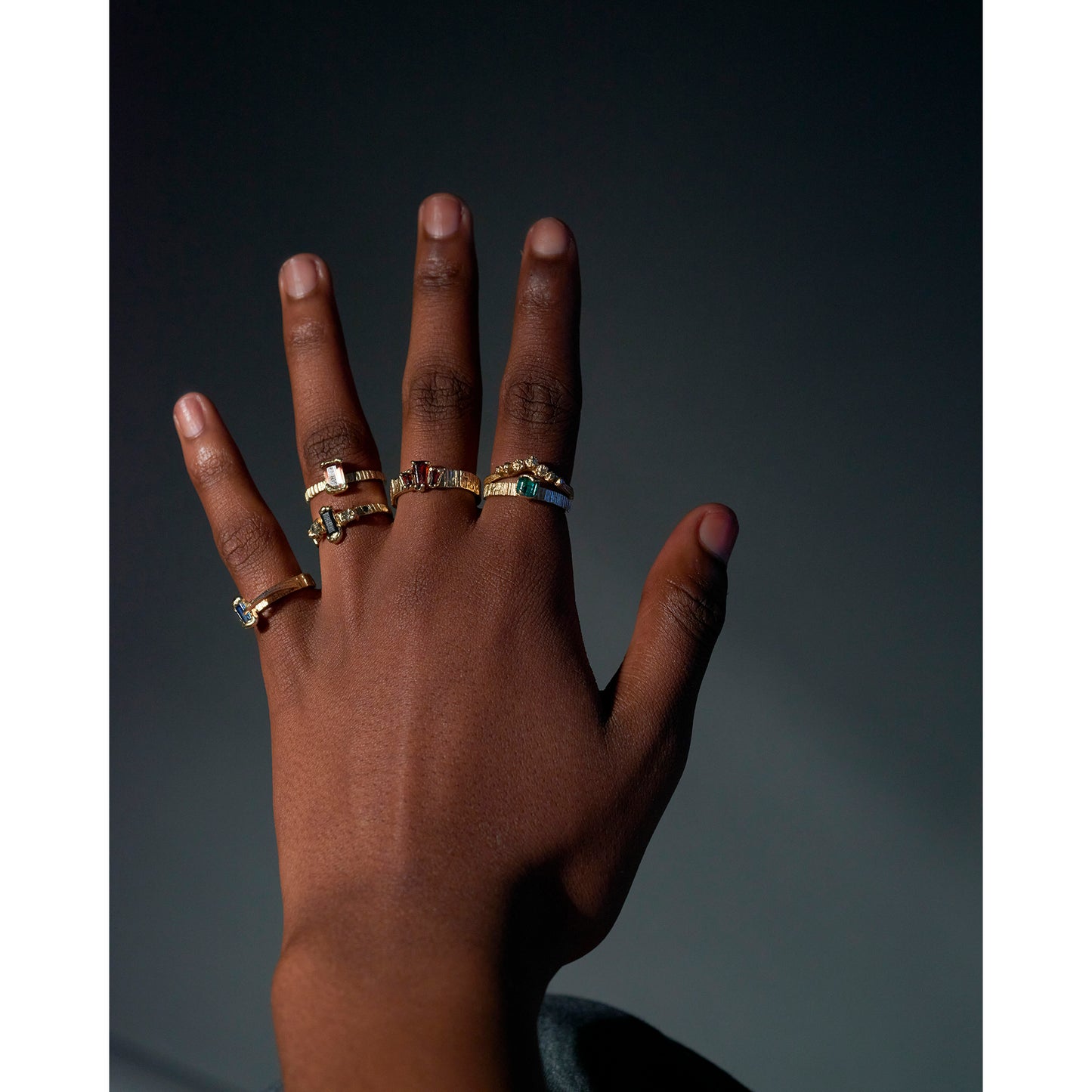 Lots of organic gold rings being worn on a models hand. 