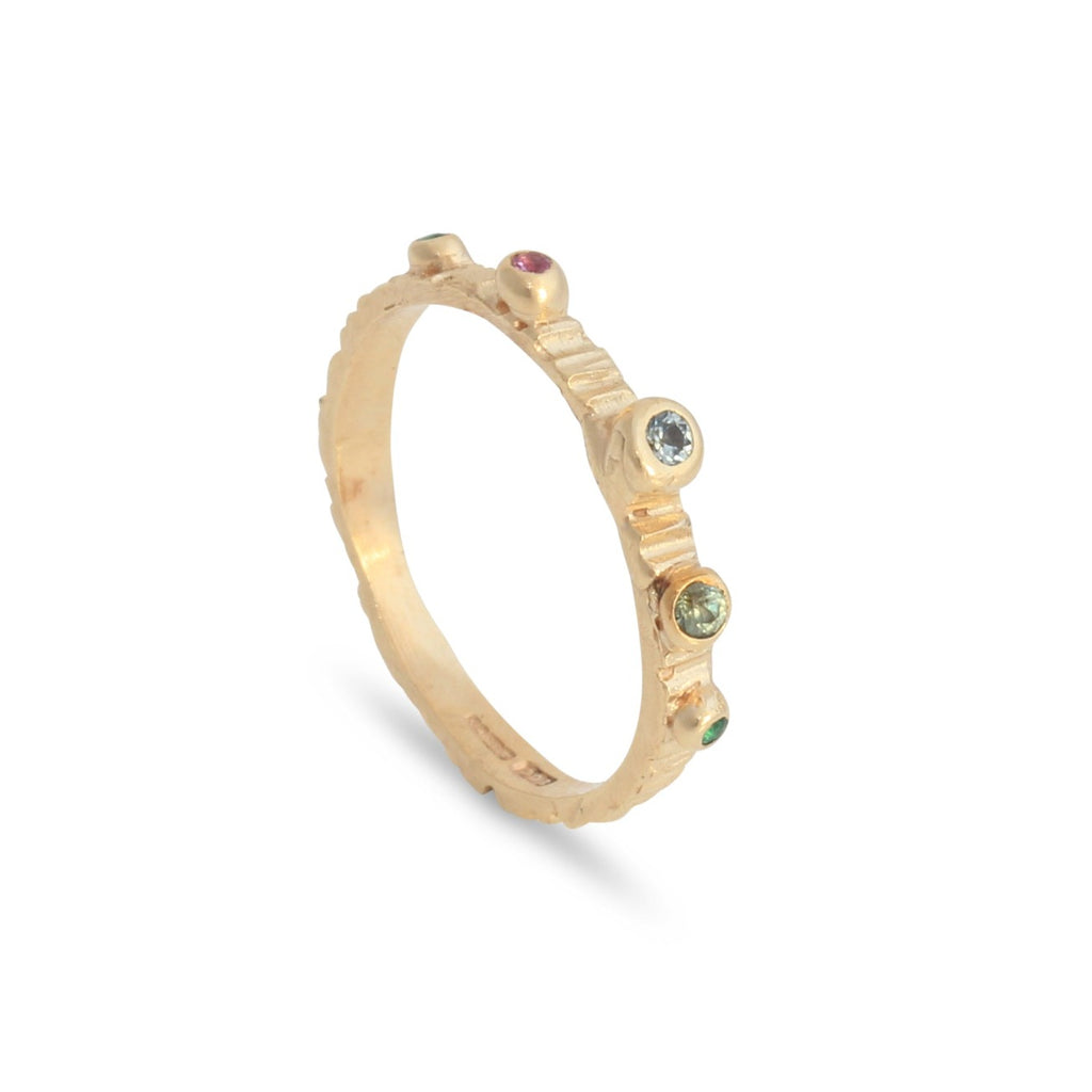 Alternative wedding band in gold set with various coloured sapphires and emerald gemstones in a rainbow of colour. 