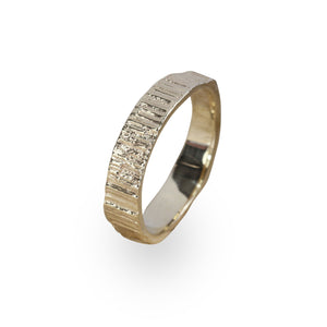 A gold ring standing alone. Alternative wedding band with organic textures and smooth polished inside.. Handmade by Irish jeweller Eily O Connell.