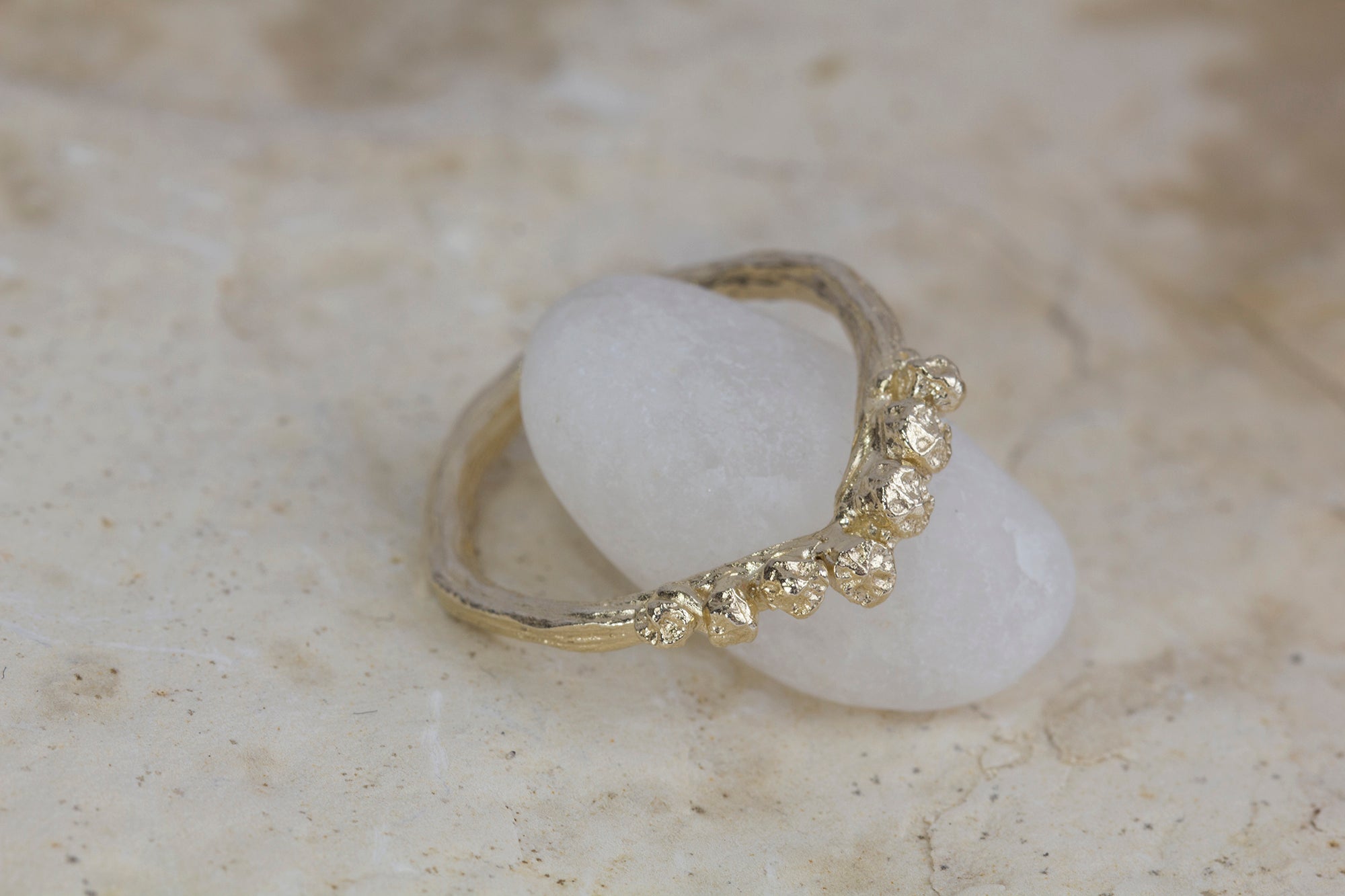 Chevron V shape gold ring cast from twigs and berries pictured on a quartz rock. 