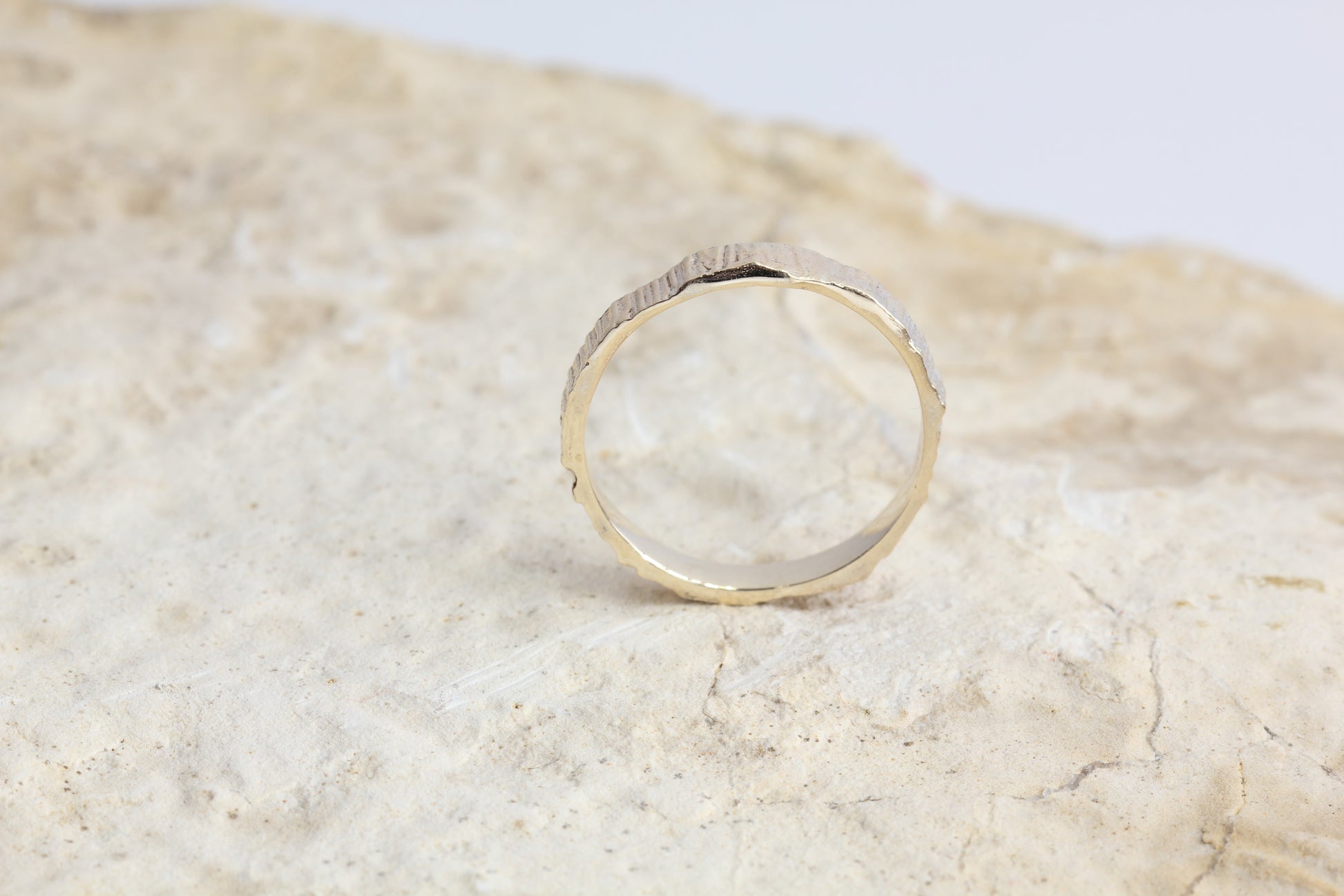 Gold wedding ring, alternative wedding band, textured wedding band handmade in Bristol shown here on a rock. 